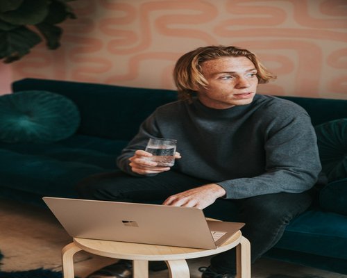 A person taking a break, drinking water while looking away from the laptop