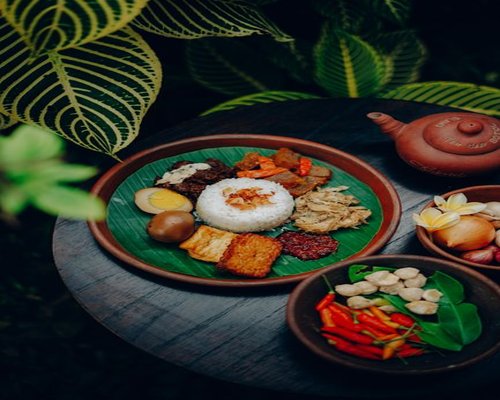 A table with a balanced traditional Indonesian meal featuring rice, vegetables, and tempeh